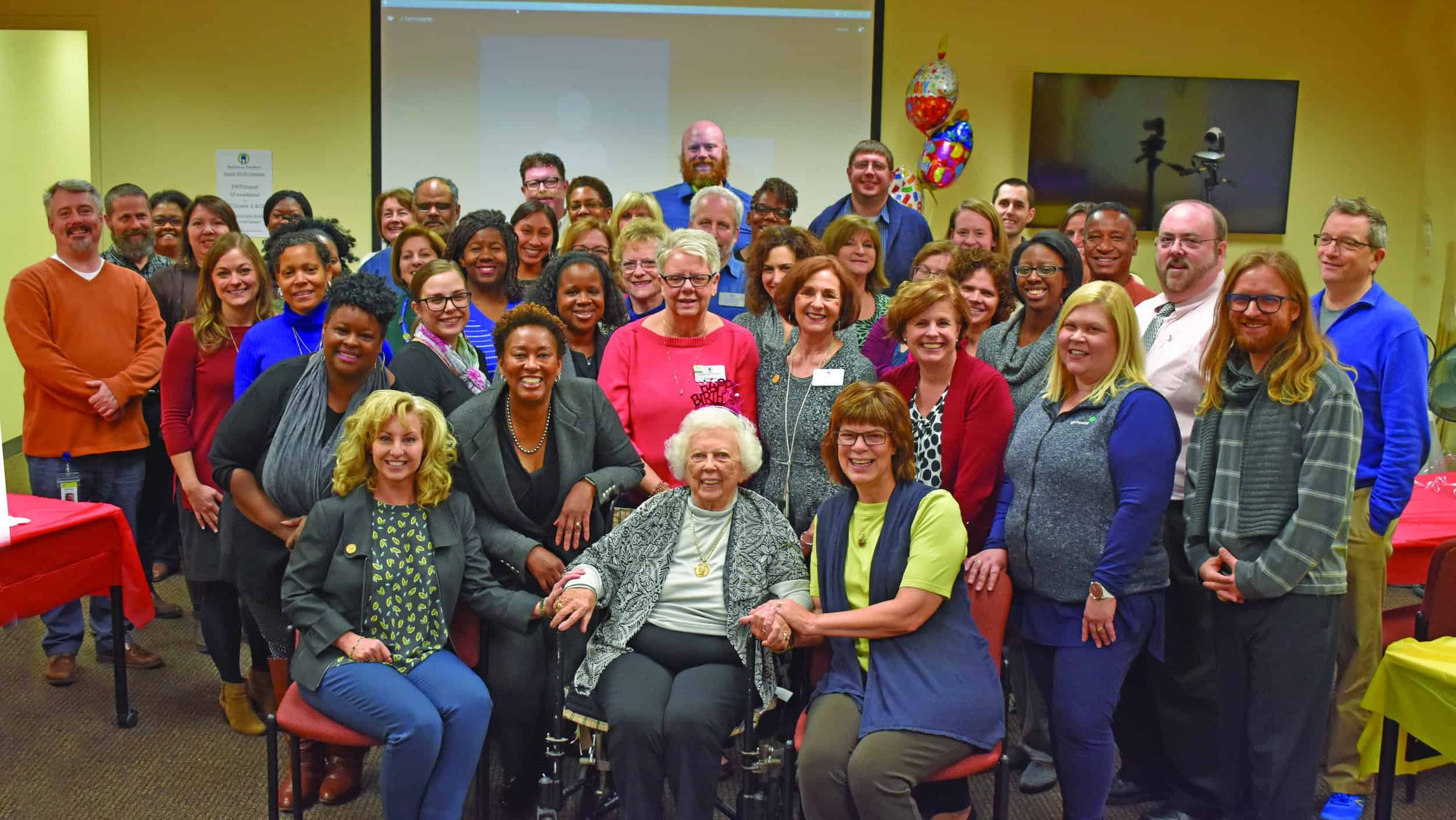 Parent educators and staff at the Parents as Teachers National Center in St. Louis, MO pose with Parents as Teachers Founder Mildred Winter (seated center) and Constance Gully, the organization’s president and CEO, (left) during Winter’s 98th birthd…