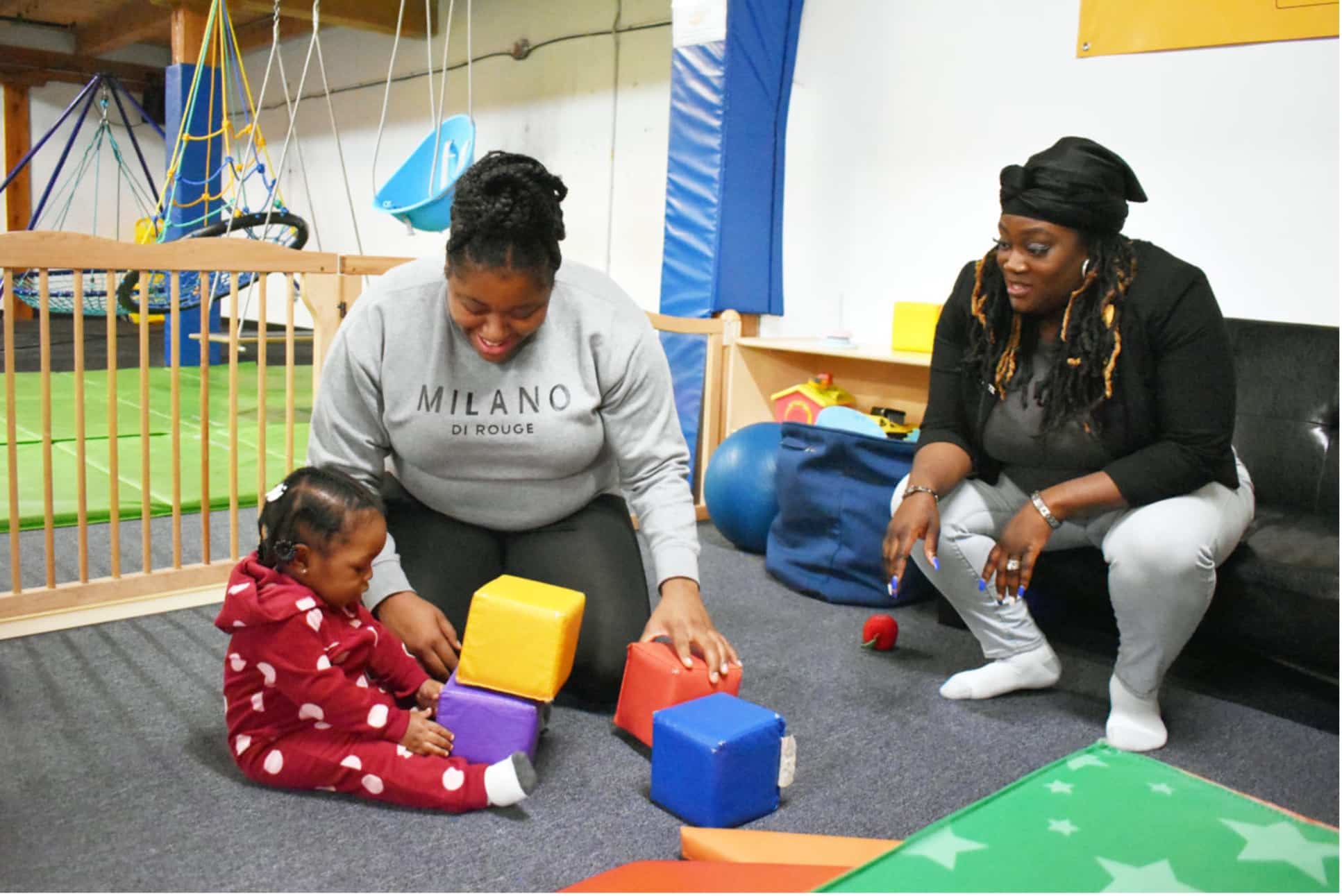 Myisha Harris, left, plays with her daughter, one-year-old Lillee, alongside Kutest Kids’s Parents as Teachers Executive Director Vonee Hill.